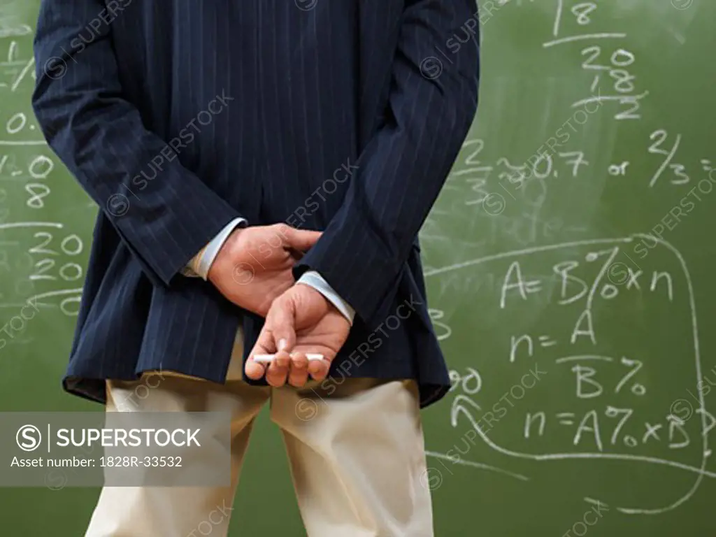 Teacher Looking at Math Problems on Blackboard   