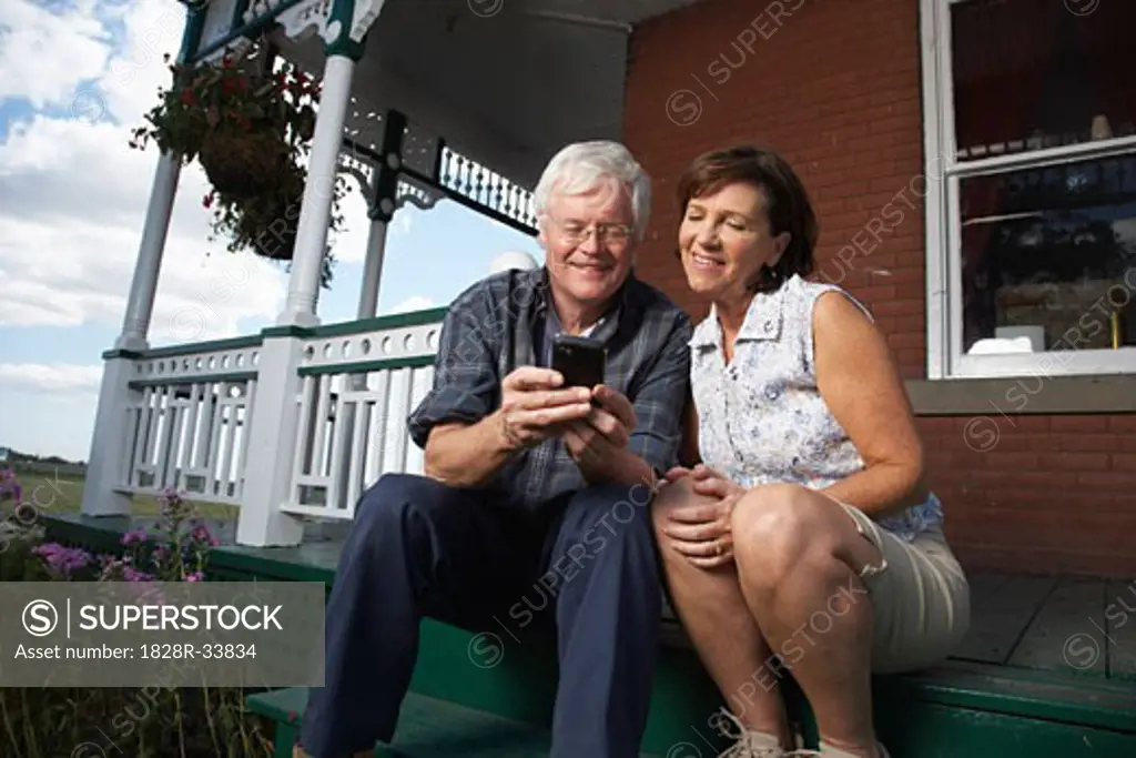 Couple with Electronic Organizer on Porch of Farmhouse   