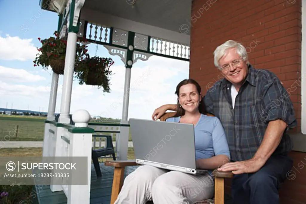 Father and Daughter with Laptop on Porch of Farmhouse   