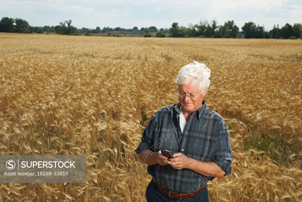 Farmer in Field with Electronic Organizer   