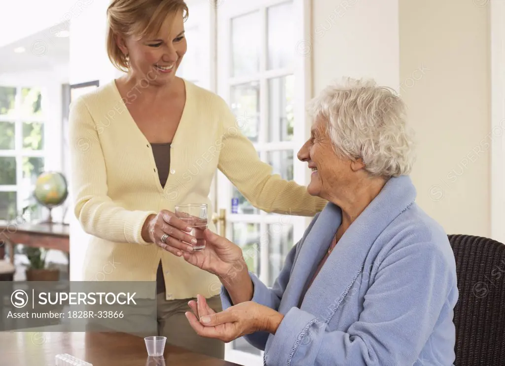 Woman Assiting Senior Woman in Taking Pills   
