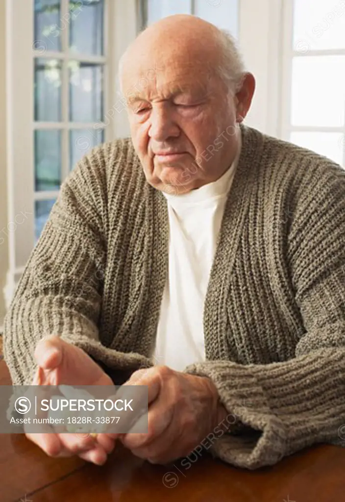 Senior Man Looking at Pill Organizer   