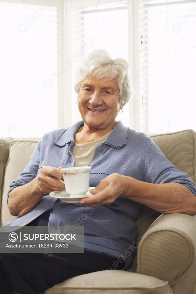 Portrait of Senior Woman Sitting on Sofa Holding Cup and Saucer   