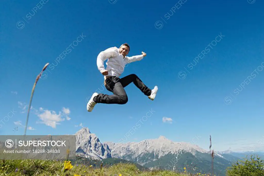Man Jumping by Mountain Range   