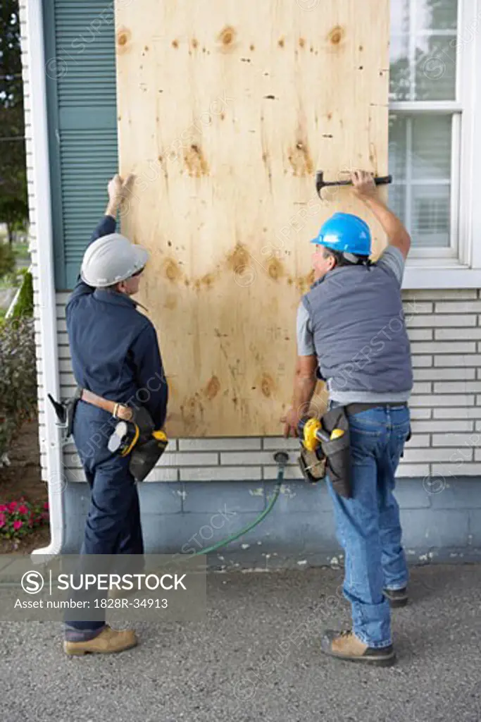 Construction Workers Covering Window with Board   
