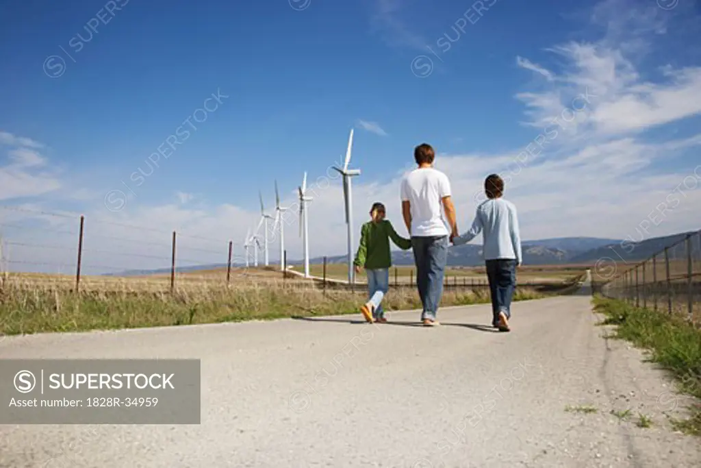 Father and Children Walking on Rural Road, next to Wind Turbines   