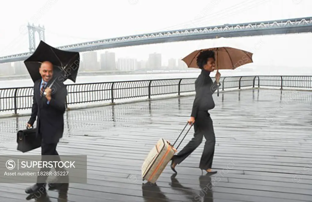 Business People Walking in Rain by Brooklyn Bridge, New York City, New York, USA   