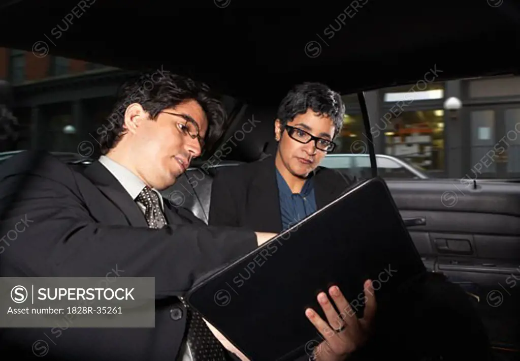 Business People Looking at Documents in Taxi, New York City, New York, USA   