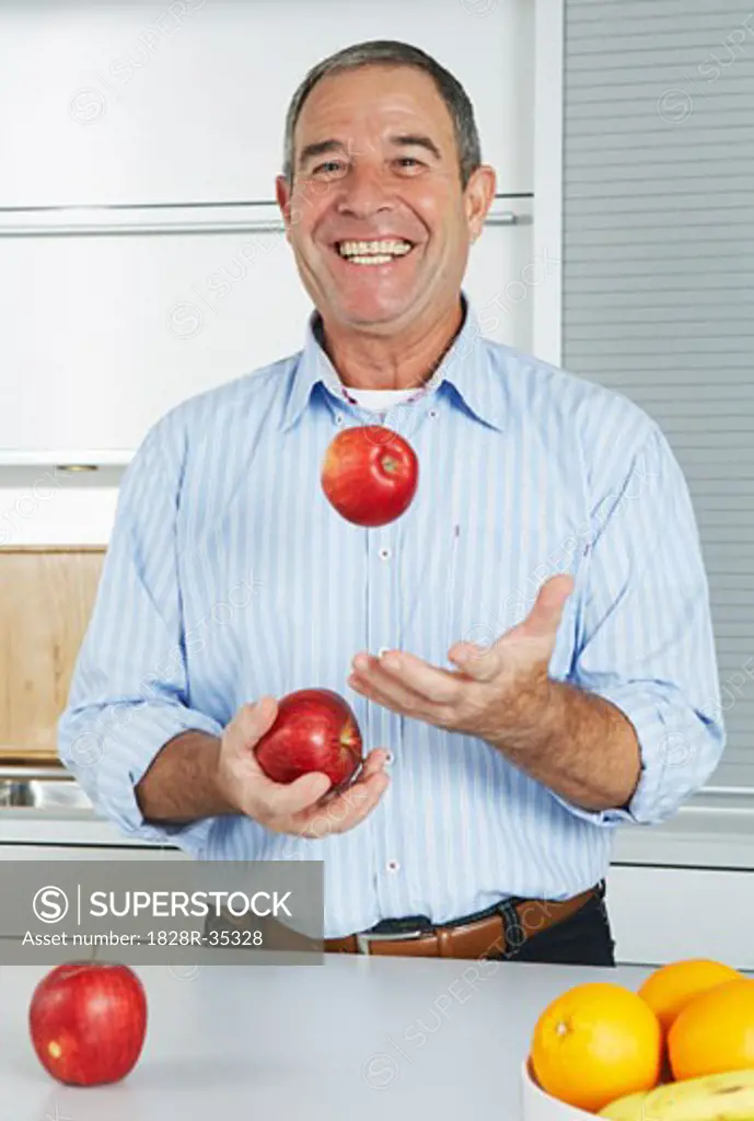 Man Juggling Apples in Kitchen   