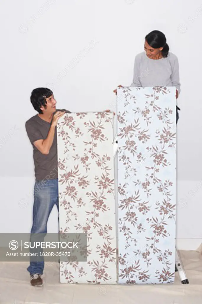 Couple Putting Up Wallpaper   