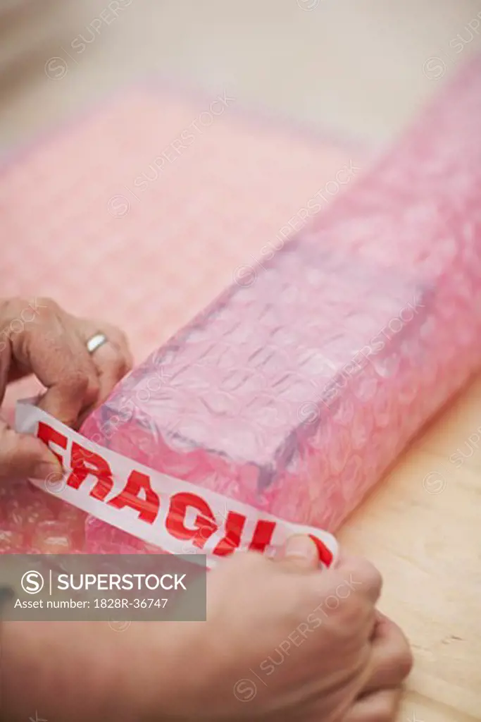 Man's Hands Wrapping Fragile Goods   