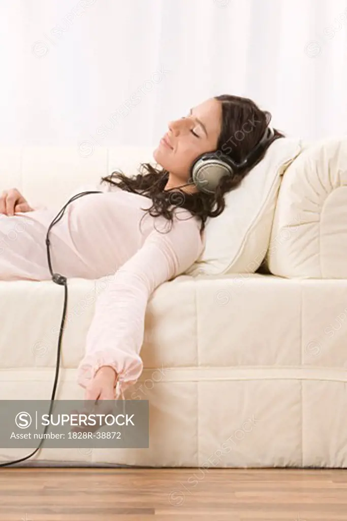 Woman Listening to Music with Headphones on Sofa   