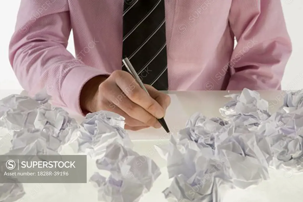 Businessman Surrounded by Crumpled Paper   