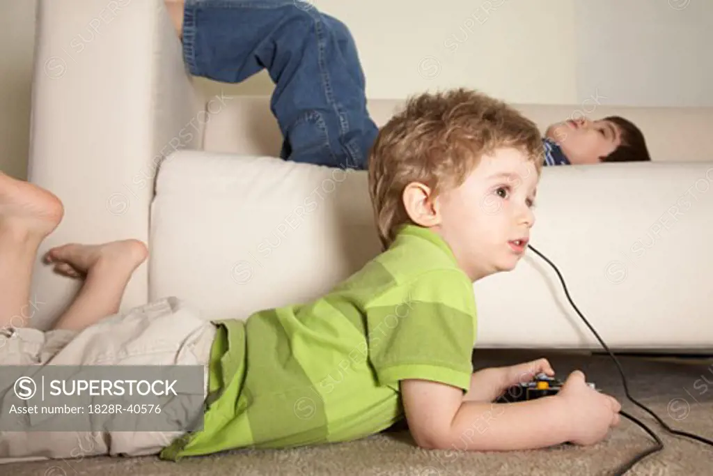 Boy Playing Video Games, Brother Lying on Sofa   