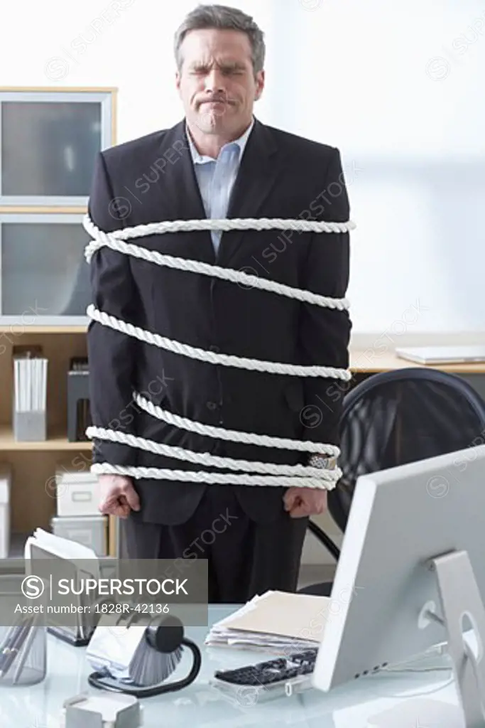 Businessman Tied Up with Rope at Desk   