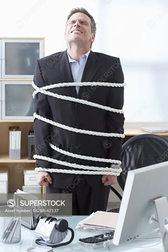 Businessman Tied Up with Rope at Desk   