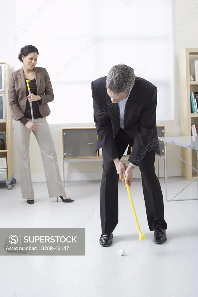 Businessman and Businesswoman Playing Golf in Office   