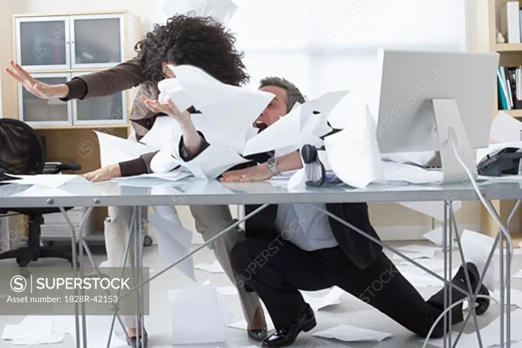 Business People Trying to Hold onto Paperwork Blowing Around on Desk   