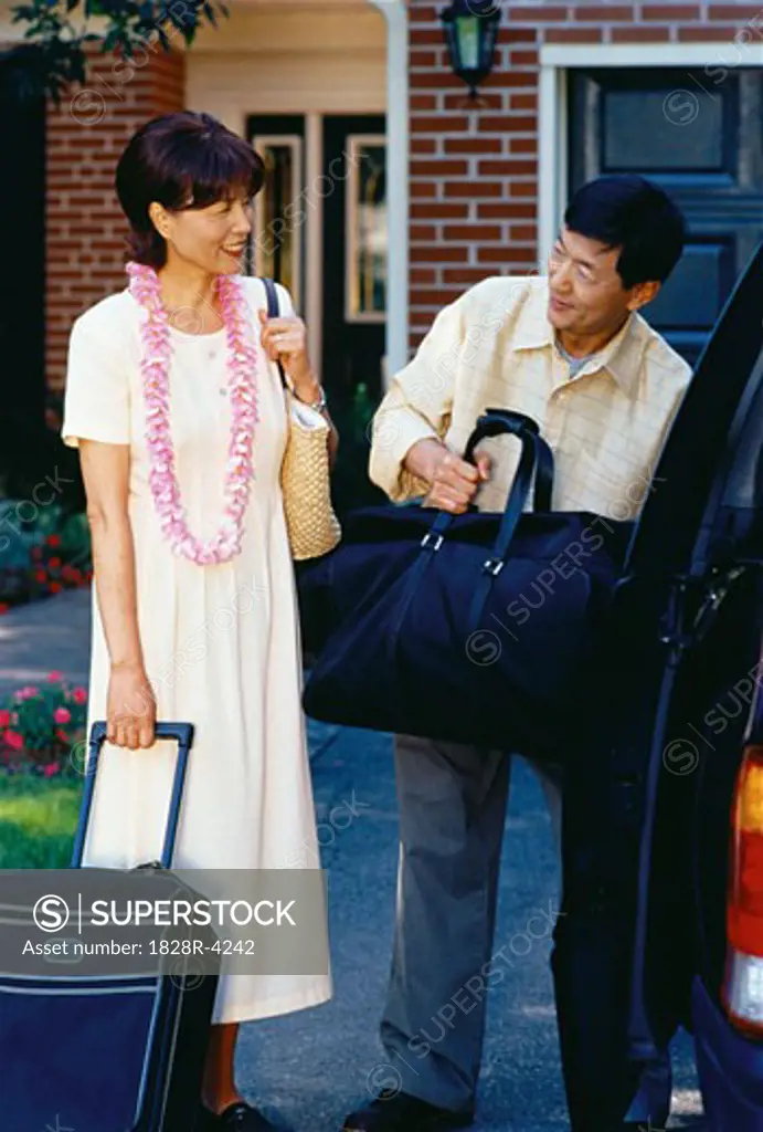 Mature Couple Unloading Luggage From Van   