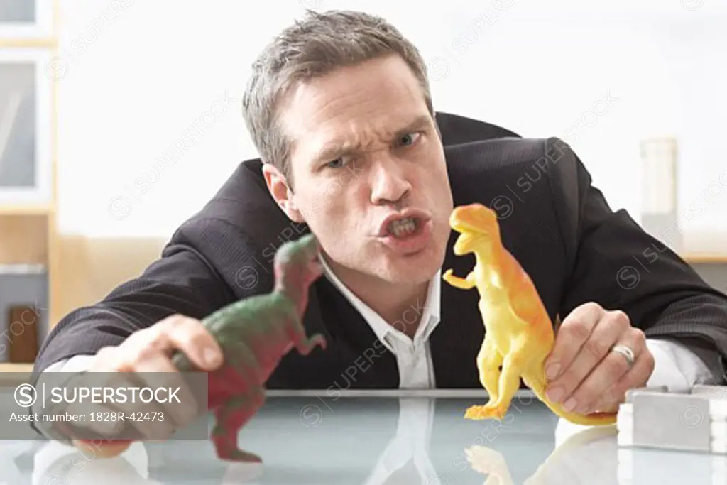 Businessman Playing with Toy Dinosaurs   