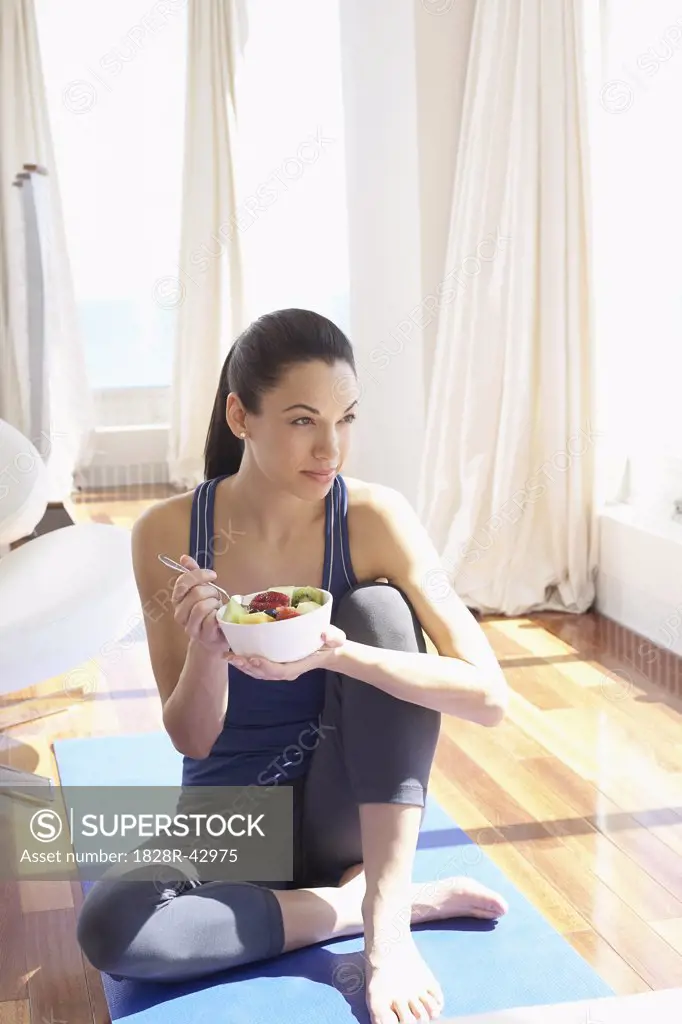 Woman on Yoga Mat with Bowl of Fruit   