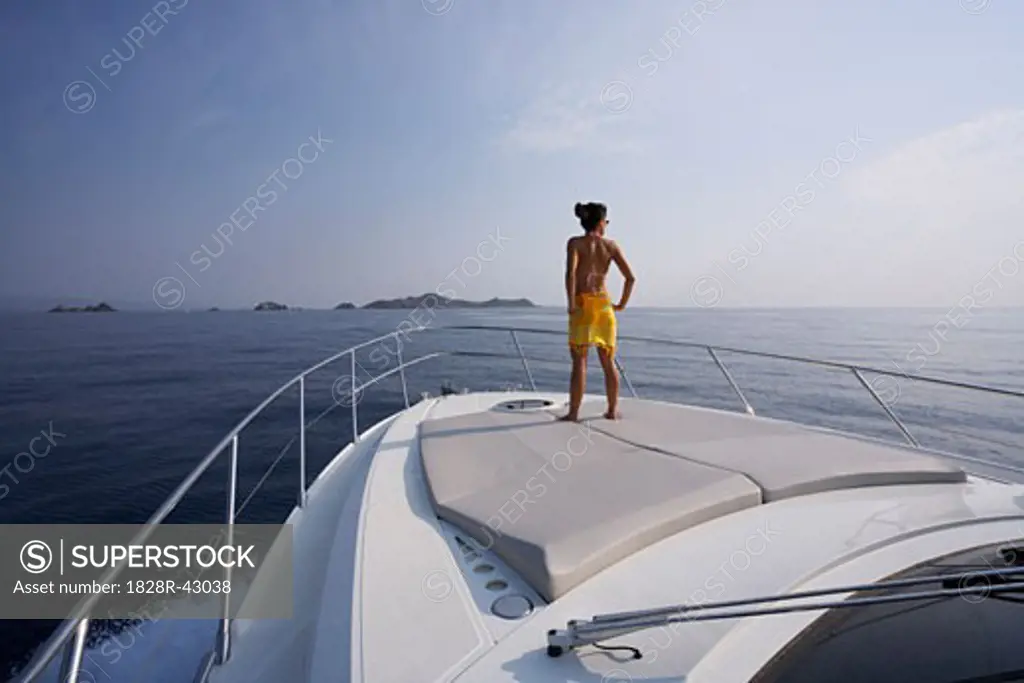 Woman Standing on Bow of Yacht, Girolata Marine Park, Corsica, France   