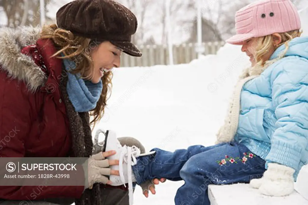 Mother Helping Daughter Put on Ice Skates   