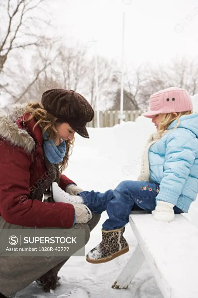 Mother Helping Daughter Put on Ice Skates   