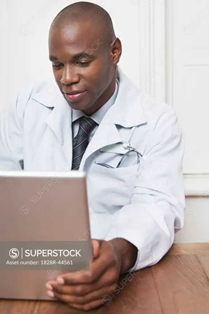 Physician Sitting Behind Desk Working on Laptop   