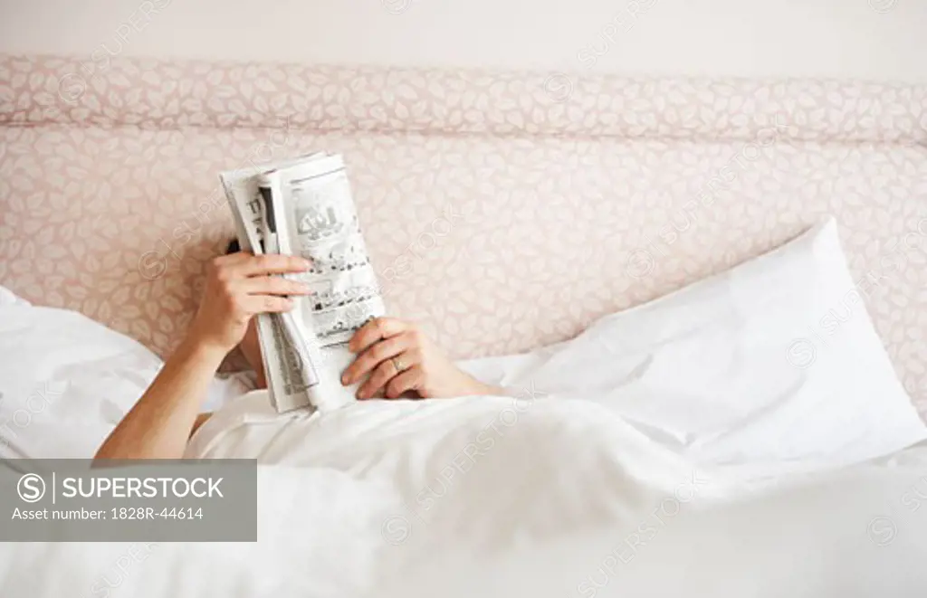 Man Reading Newspaper in Bed   