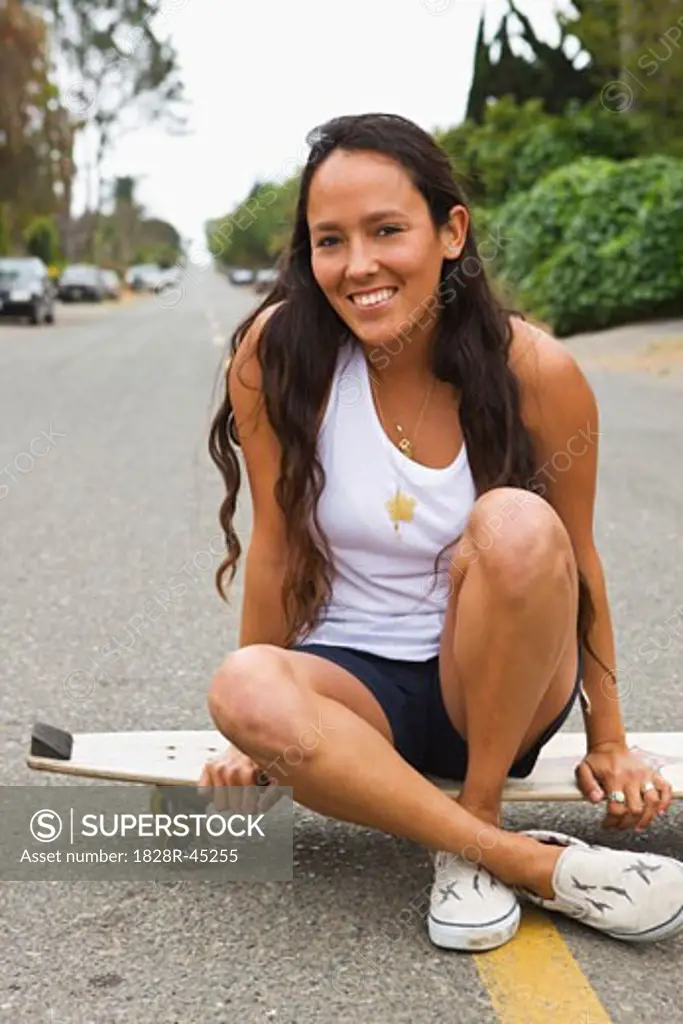 Woman sitting on Skateboard   
