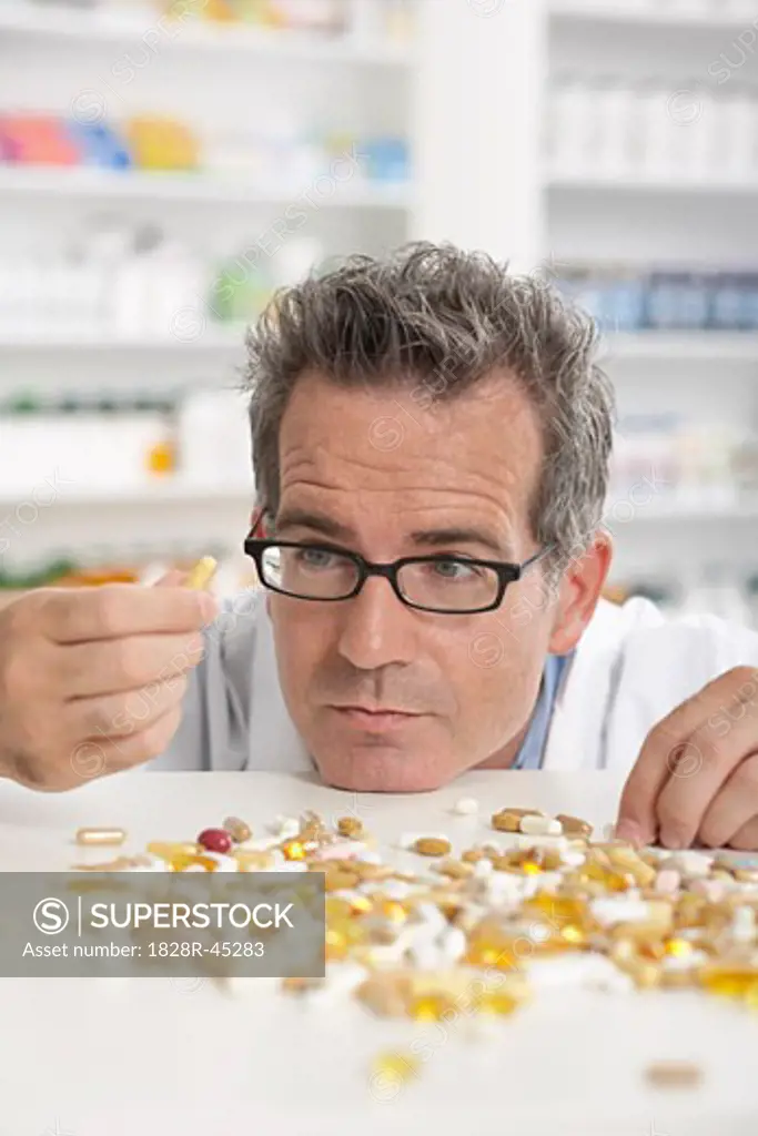 Pharmacist Looking at Pile of Pills   
