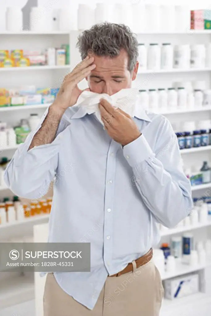 Man in Pharmacy Blowing Nose   