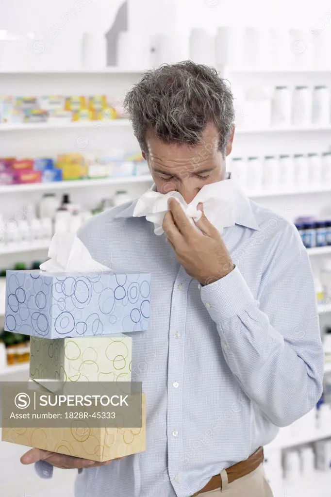 Man in Pharmacy Blowing Nose, Carrying Boxes of Tissue   
