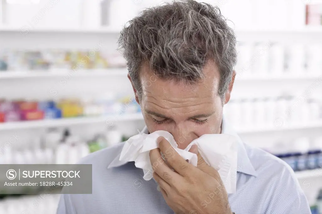 Man in Pharmacy Blowing Nose   