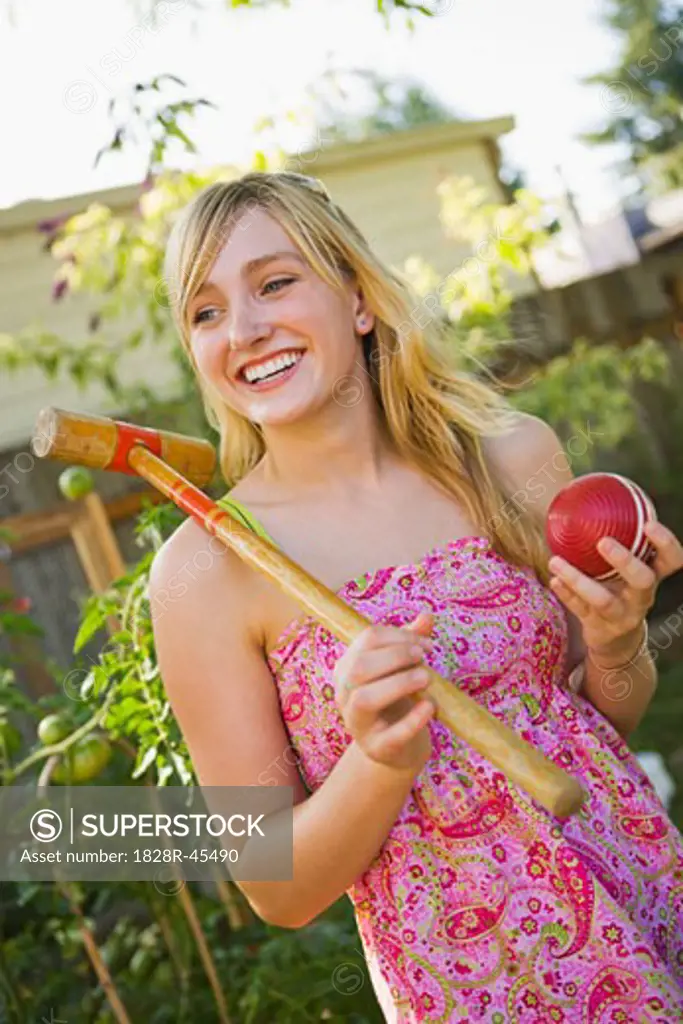 Woman in Backyard with Croquet Mallet and Ball, Portland, Oregon, USA   
