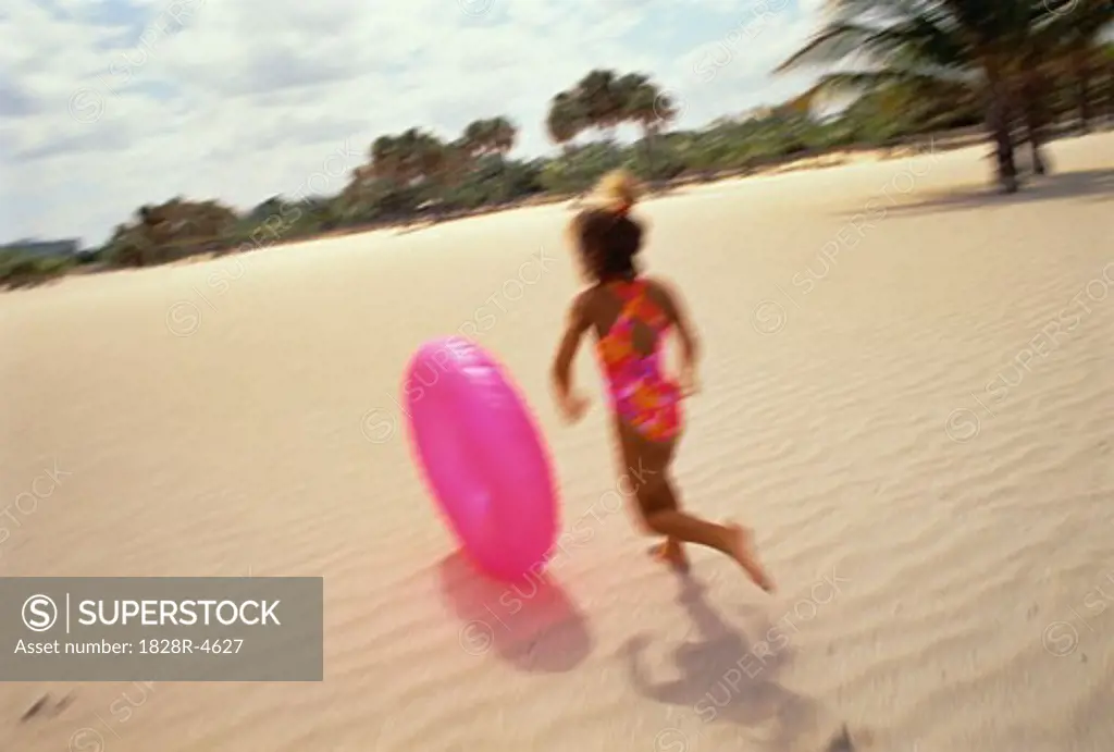 Back View of Girl in Swimwear Chasing Inner Tube on Beach, Miami Beach, Florida, USA   