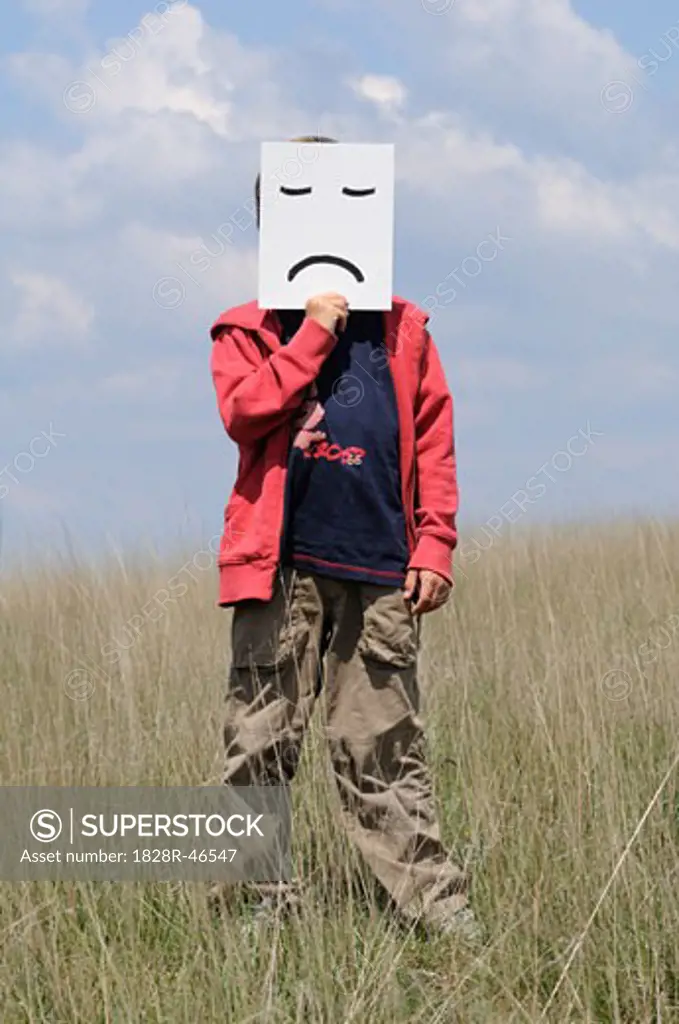 Boy in Field Holding Frown Face   