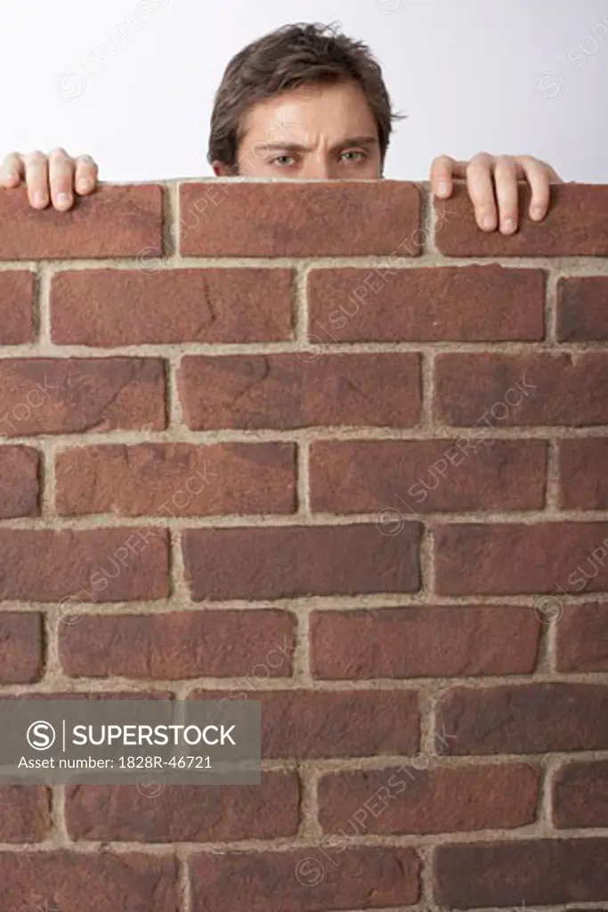 Man Looking Over Brick Wall   