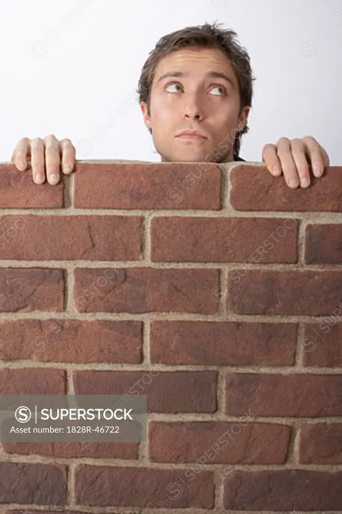 Man Looking Over Brick Wall   