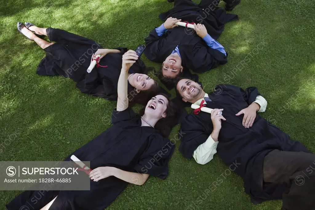 College Graduates Lying on Ground Taking Pictures With Camera Phone   