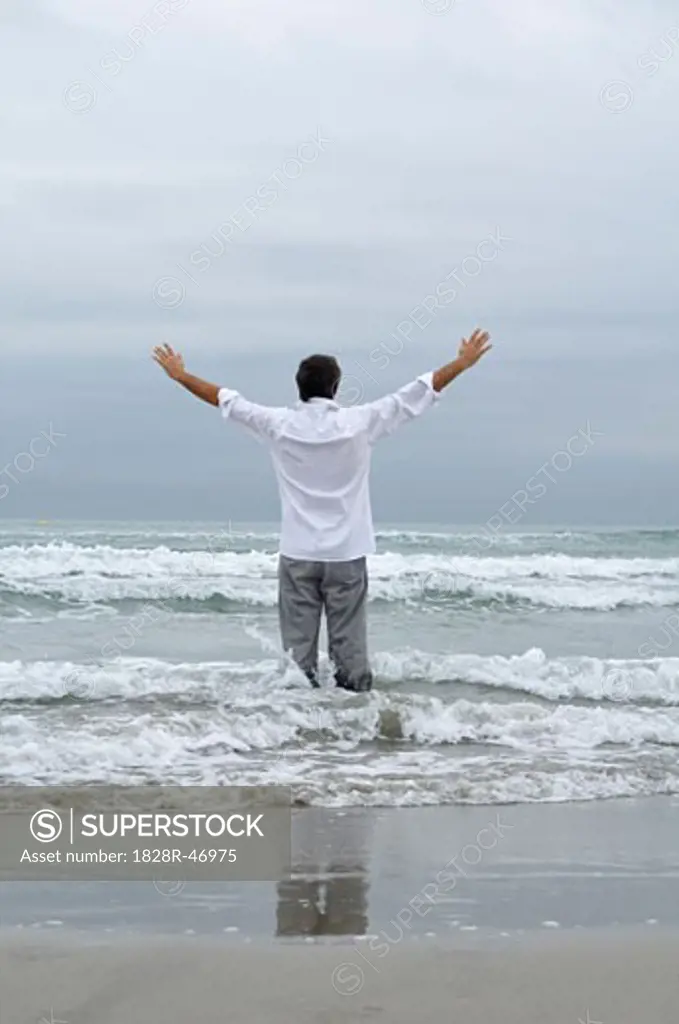 Man Standing in Waves on Beach   