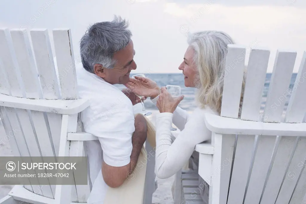 Couple with Wine Sitting in Chairs on Beach   
