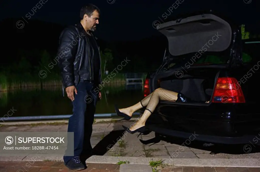 Man Looking at Dead Body in Trunk of Car   