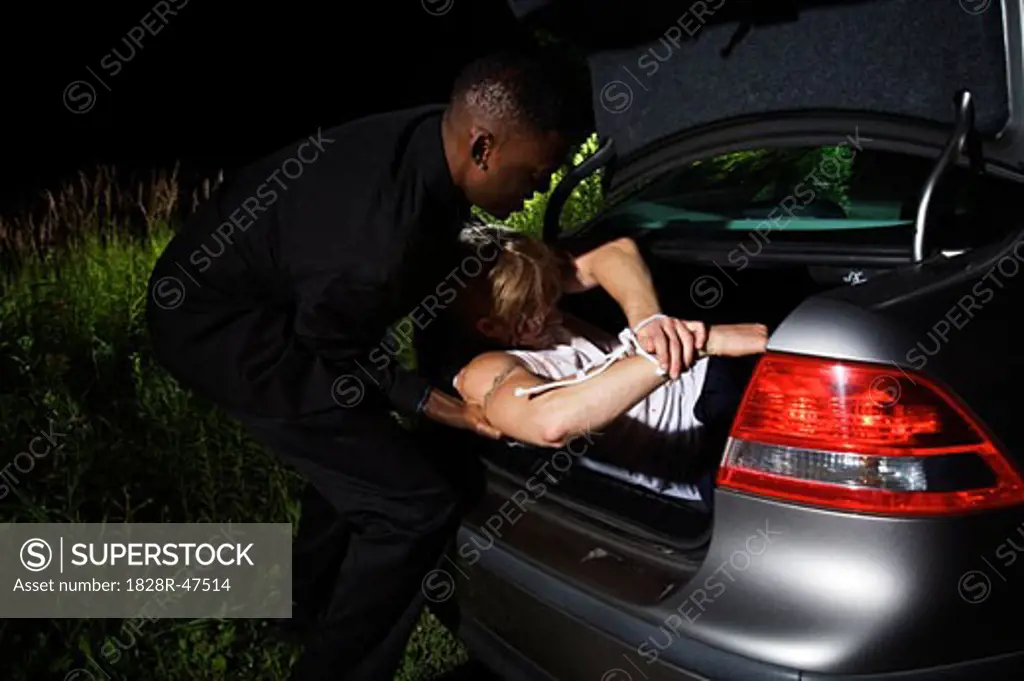 Man Putting Body in Trunk of Car   
