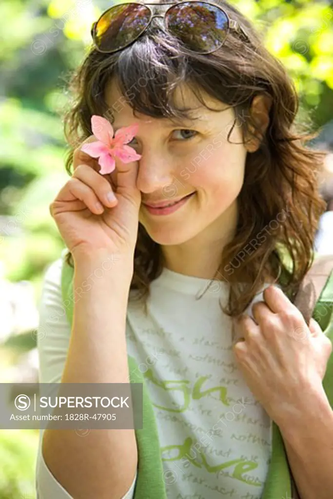 Portrait of Woman Holding a Flower Over Her Eye, San Francisco, California, USA   