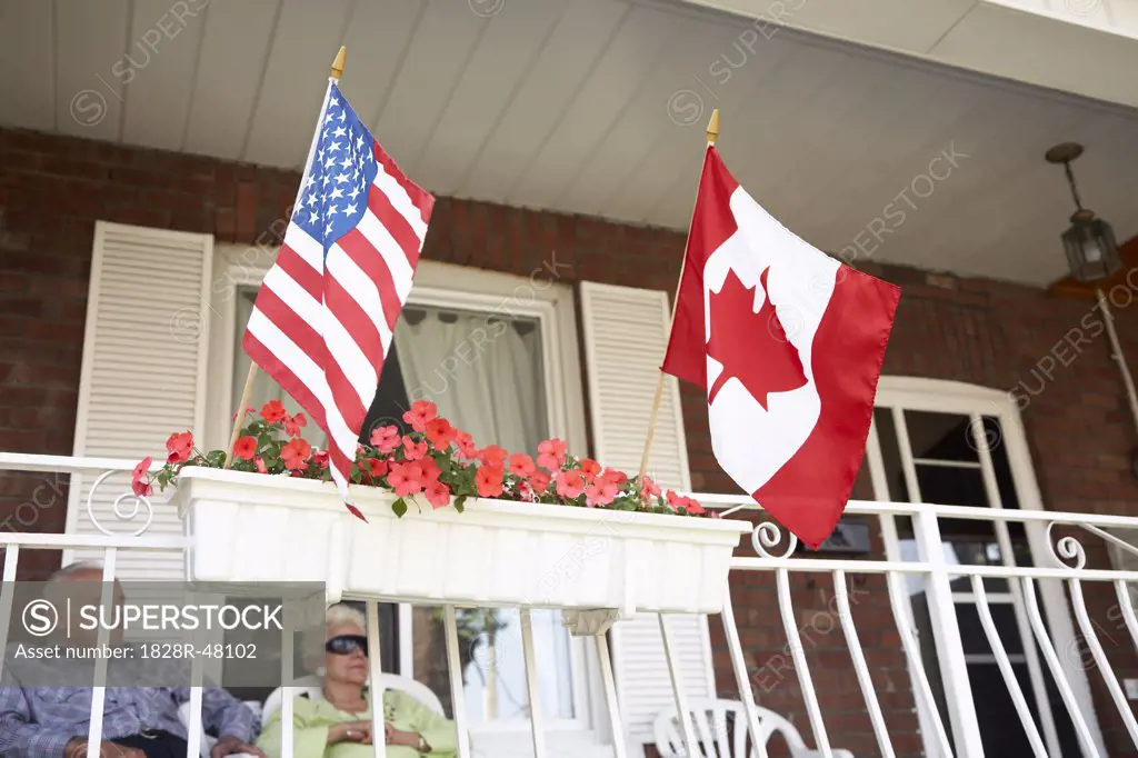 Senior Couple on Front Porch with American and Canadian Flags   
