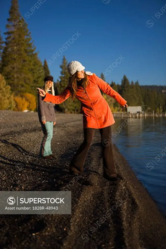 Friends Skipping Stones on Shoreline, Lake Tahoe, California, USA   