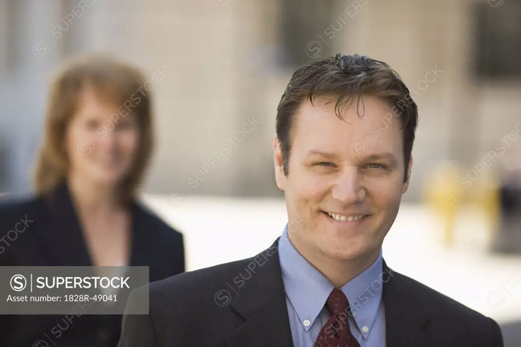 Portrait of Businessman Outdoors,  Businesswoman in the Background   