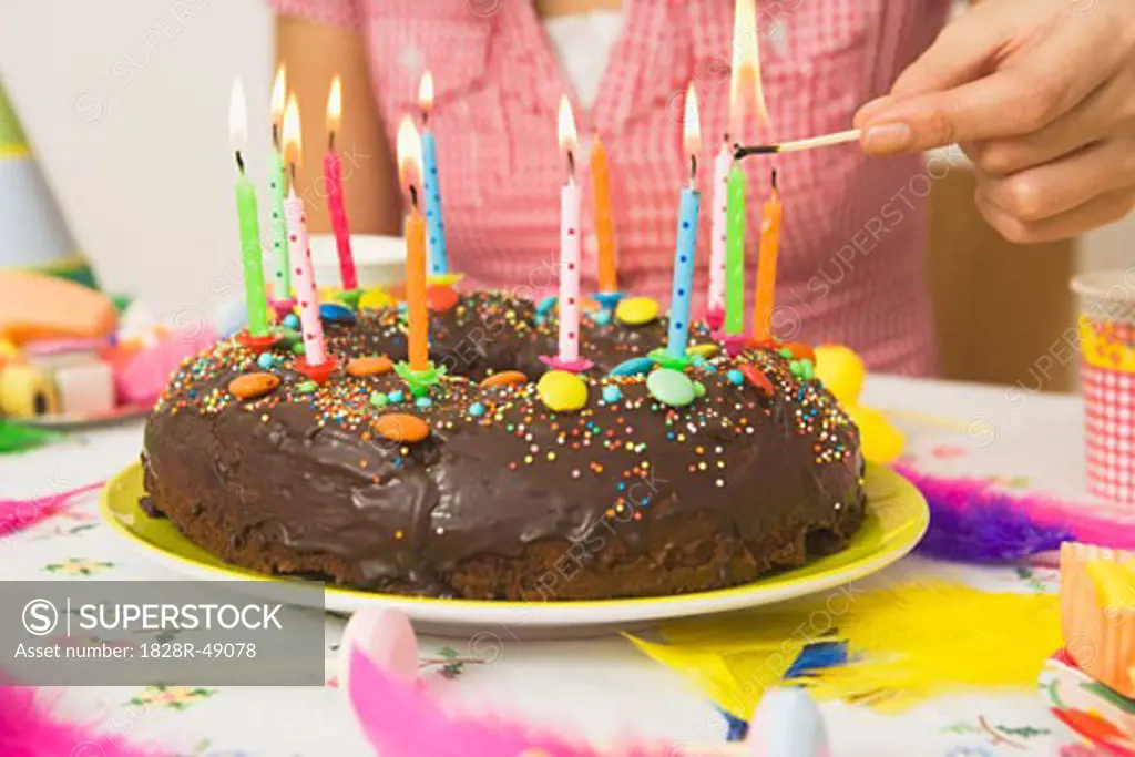 Woman Lighting Candles on Birthday Cake   